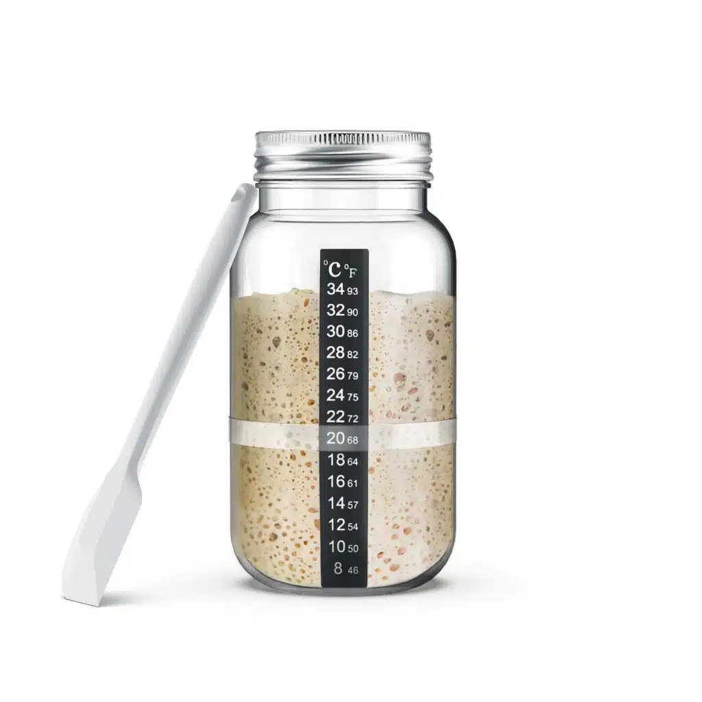 Zuurdesemstarter met glazen bokaal, temperatuurstrip en witte silicone spatula
